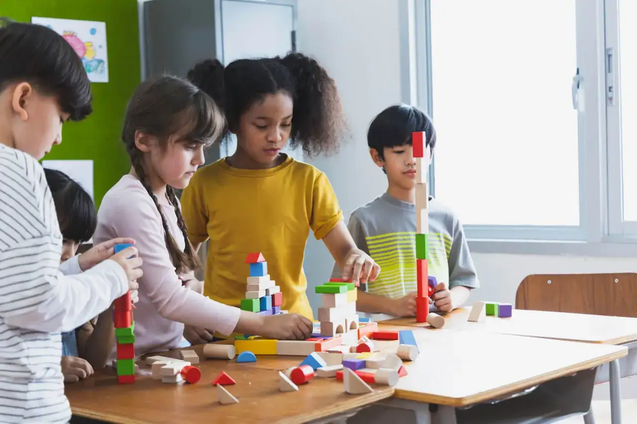 Kinder bauen mit bunten Holzklötzen, ein Beispiel für interaktiven Unterricht, der Kreativität und Teamwork fördert.