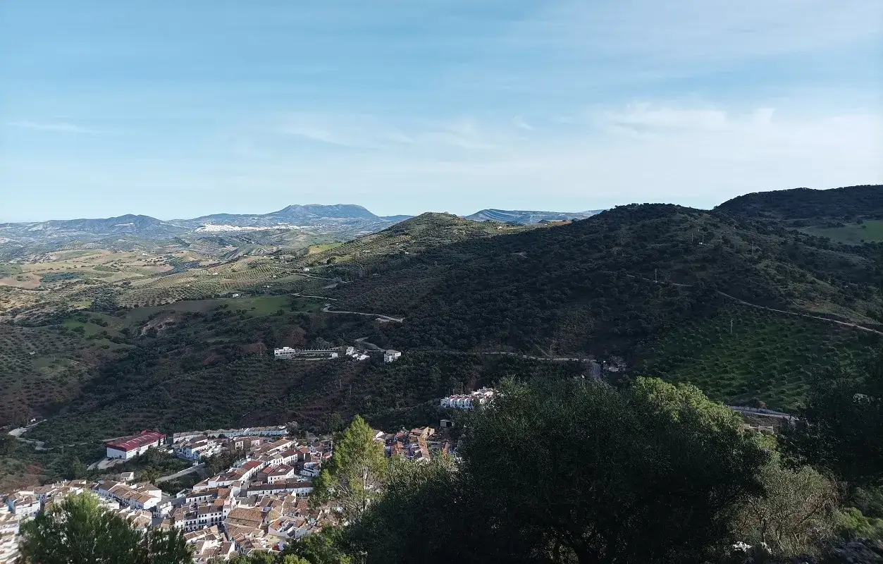 Blick auf das wei&szlig;e Dorf El Gastor in Andalusien, umgeben von gr&uuml;nen H&uuml;geln und Olivenhainen.
