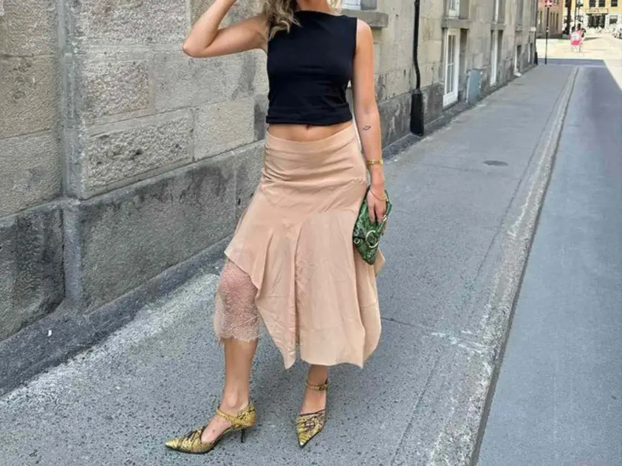 Ein beiger Satinrock kombiniert mit schwarzem Crop-Top und auffälligen Schuhen.