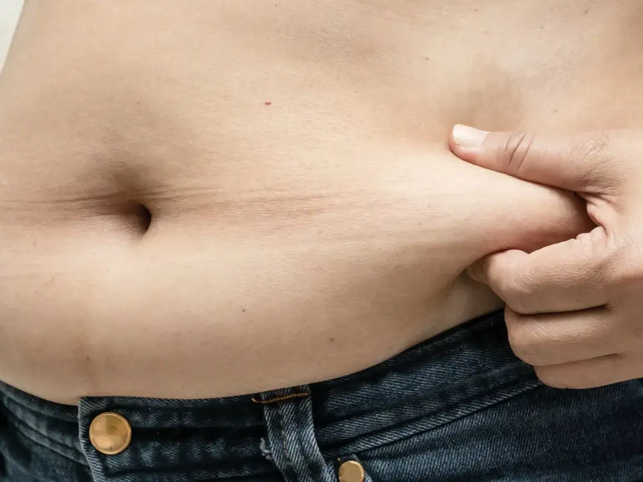 Dłoń ściska fałd sk&oacute;ry na brzuchu, przypominając kształtem żabi brzuch. Wątroba może być obciążona nadmiarem tkanki tłuszczowej.