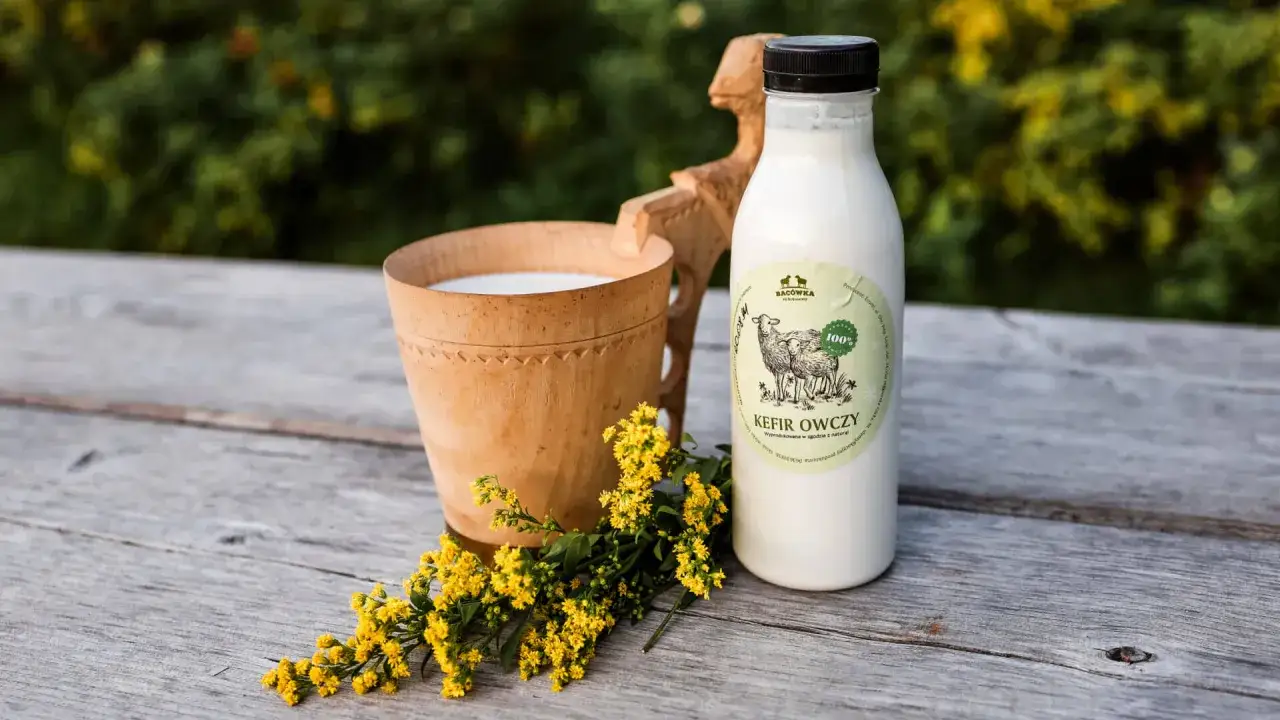 Kefir owczy w butelce i drewnianym kubku, obok ż&oacute;łte kwiaty. To jest żętyca, co to za nap&oacute;j?