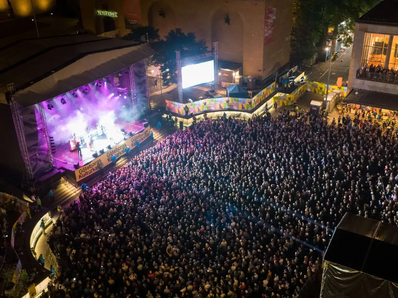 Stor publik njuter av konserter i Göteborg. En scen med band och ljus lyser upp kvällen.
