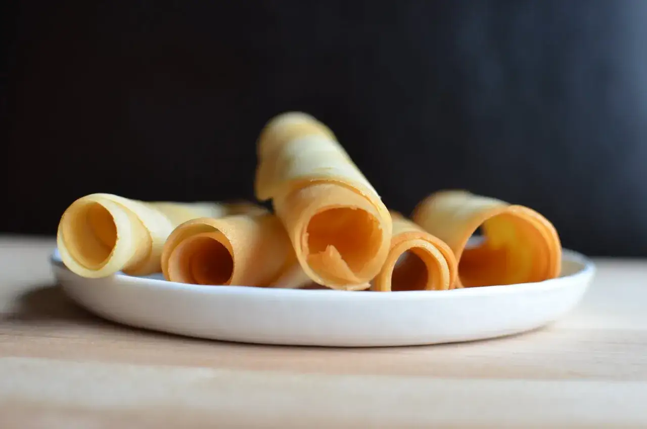 Krispiga rullade kex på en vit tallrik, perfekta för ett enkelt tuile recept.