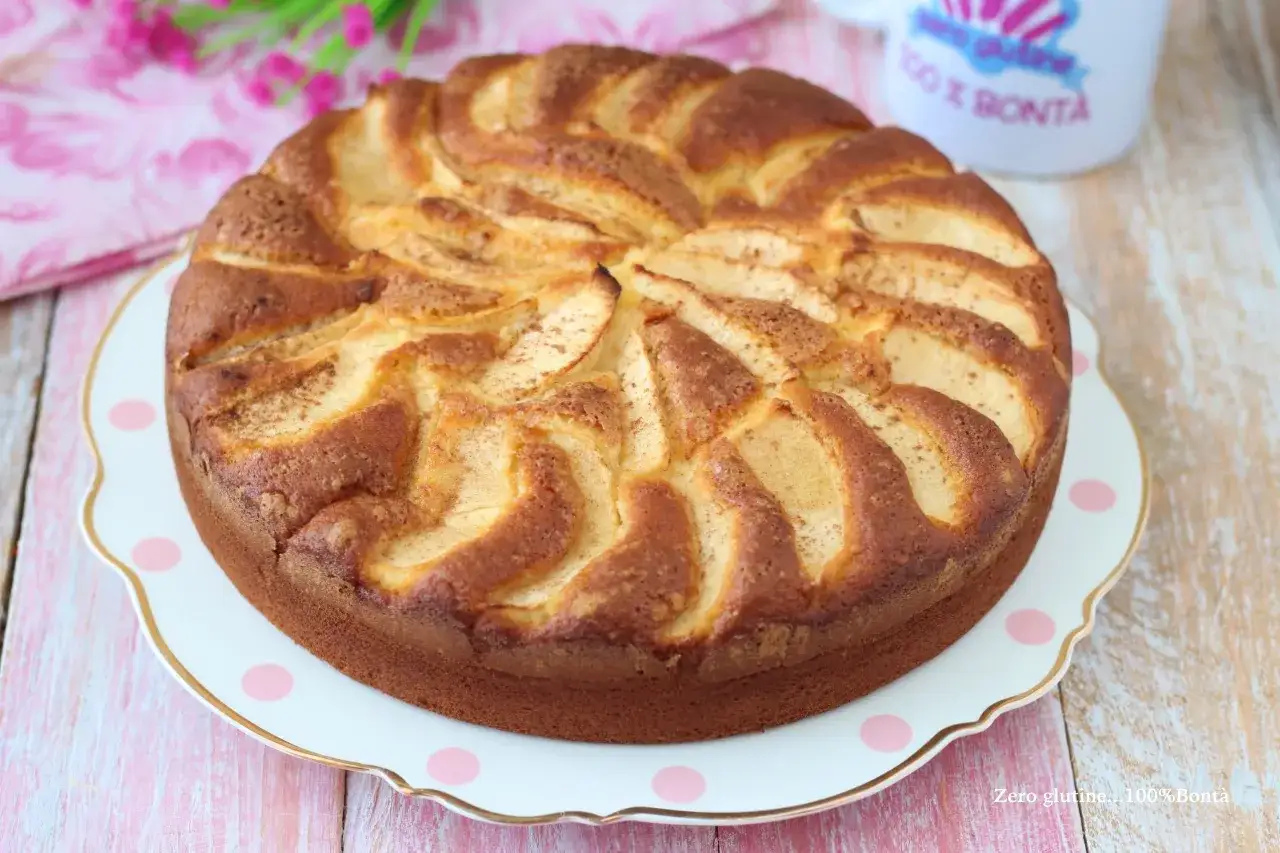 Una deliziosa torta di mele senza glutine, con mele disposte a spirale sulla superficie dorata, pronta per essere gustata.