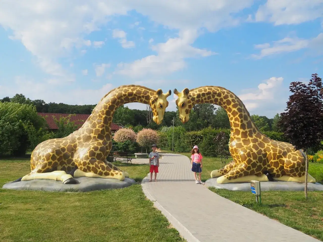Dzieci pozują między gigantycznymi żyrafami w parku rozrywki Zawada.