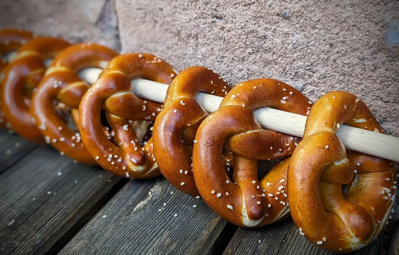 Frisch gebackene Brezen mit Salz bestreut, auf Holzbrettern liegend.