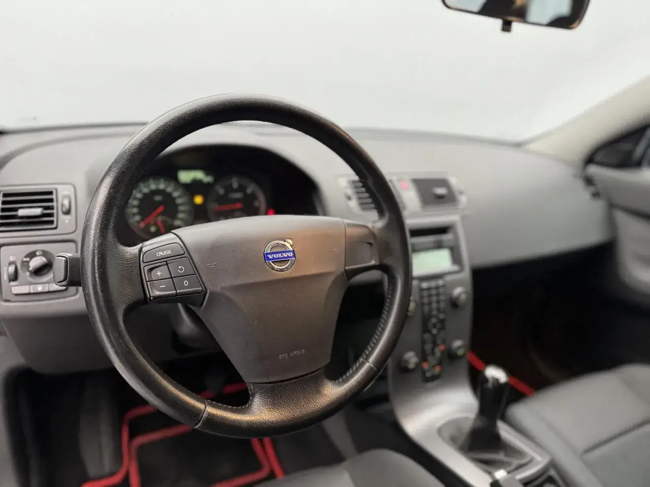 Wnętrze Volvo V50 2.0D: kierownica z przyciskami tempomatu, deska rozdzielcza i dźwignia zmiany biegów.