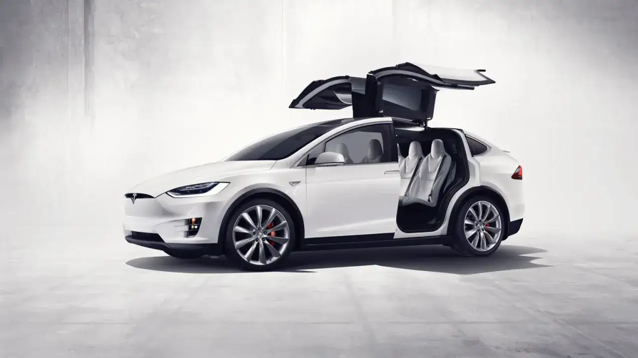 Biały Tesla X z otwartymi drzwiami typu falcon i widocznymi białymi siedzeniami.