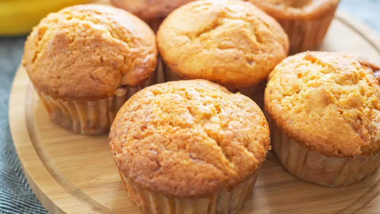 Saftige Muffins mit Quark, goldbraun gebacken, auf einem Holzbrett arrangiert.