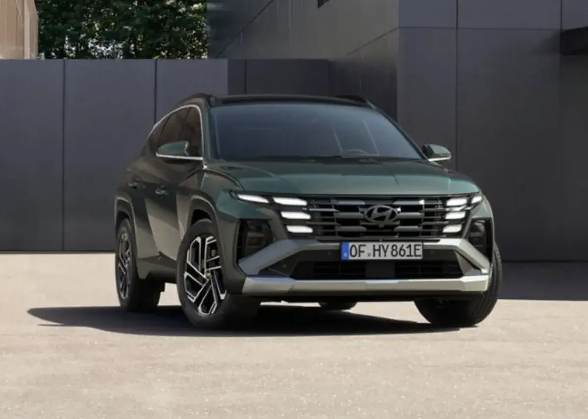 Ein gr&uuml;ner Hyundai Tucson, bereit f&uuml;r 2026, steht vor einer modernen Fassade.