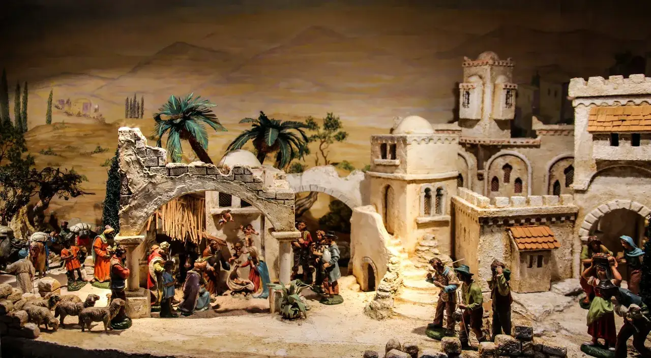Scena di presepi italiani con pastori, pecore e un villaggio in stile mediorientale.