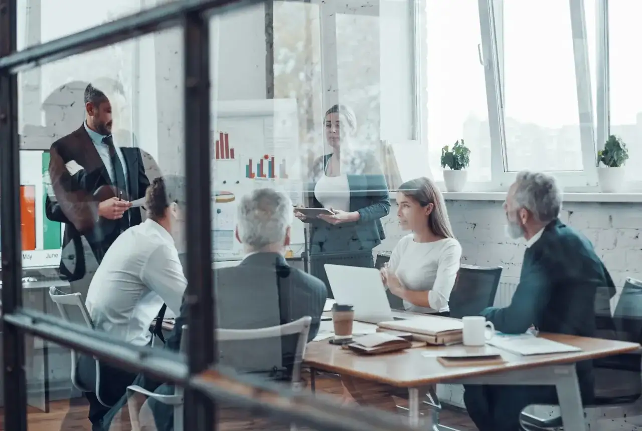 Un consulente HR guida un team in una riunione strategica, analizzando grafici e dati per ottimizzare le risorse umane.
