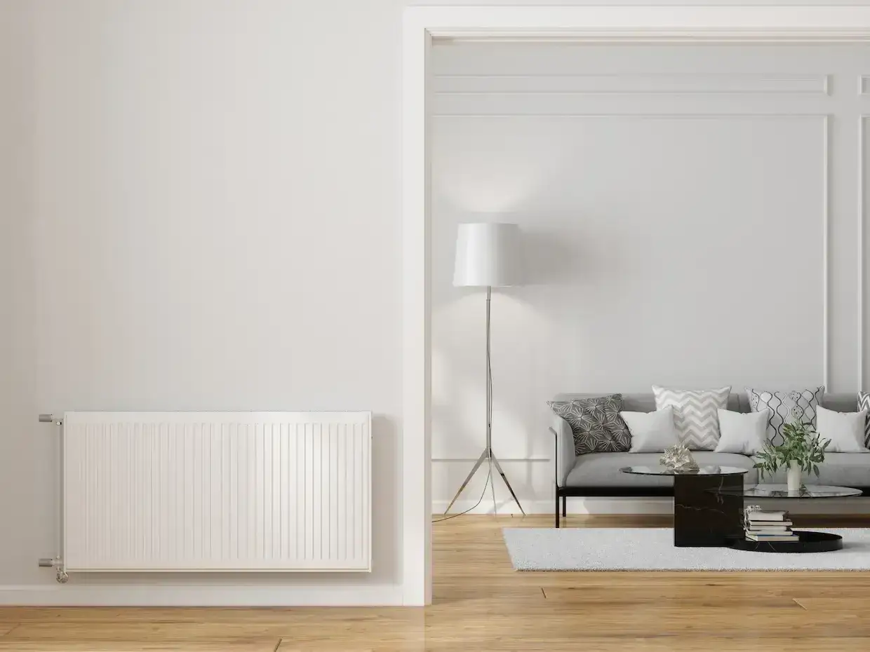 Un radiateur blanc dans un salon moderne. Faut-il changer les radiateurs avec une pompe &agrave; chaleur pour un chauffage plus &eacute;cologique ?