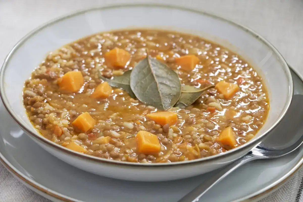 Un reconfortante plato de lentejas con arroz, trozos de calabaza y hojas de laurel.