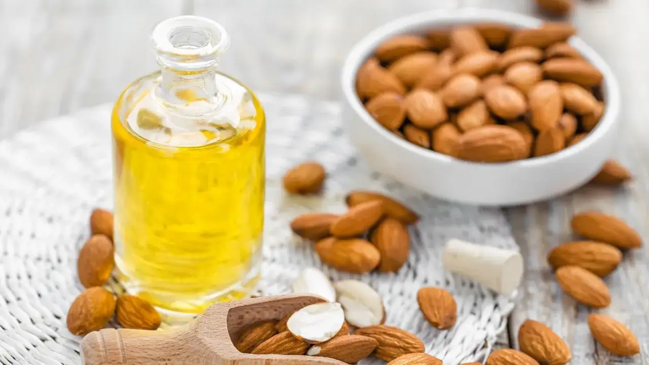 Olio di mandorle, un rimedio naturale per le cicatrici chirurgiche. Mandorle e olio in una bottiglia su un tessuto bianco.