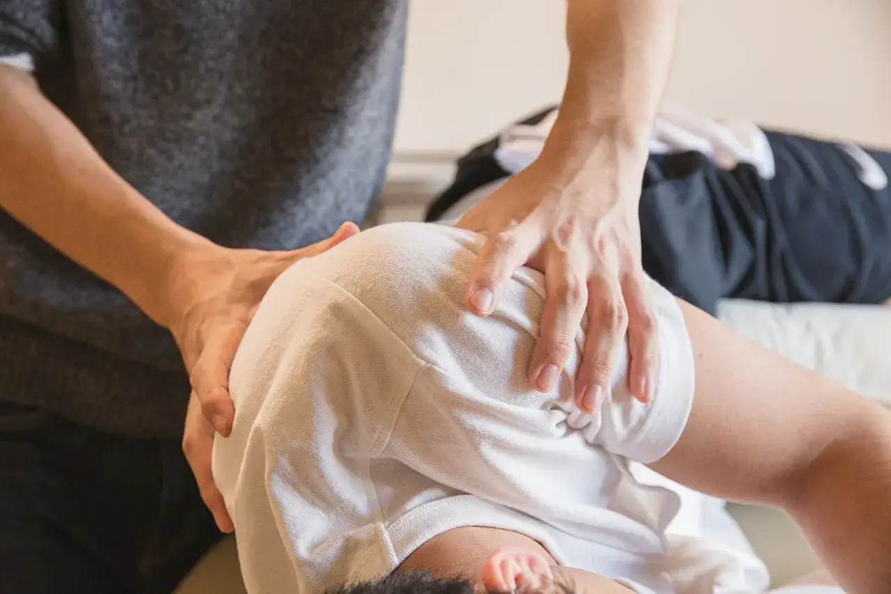 Fizjoterapeuta masuje ramię pacjenta. Mydocalm forte na co? Na bóle mięśni i napięcia.