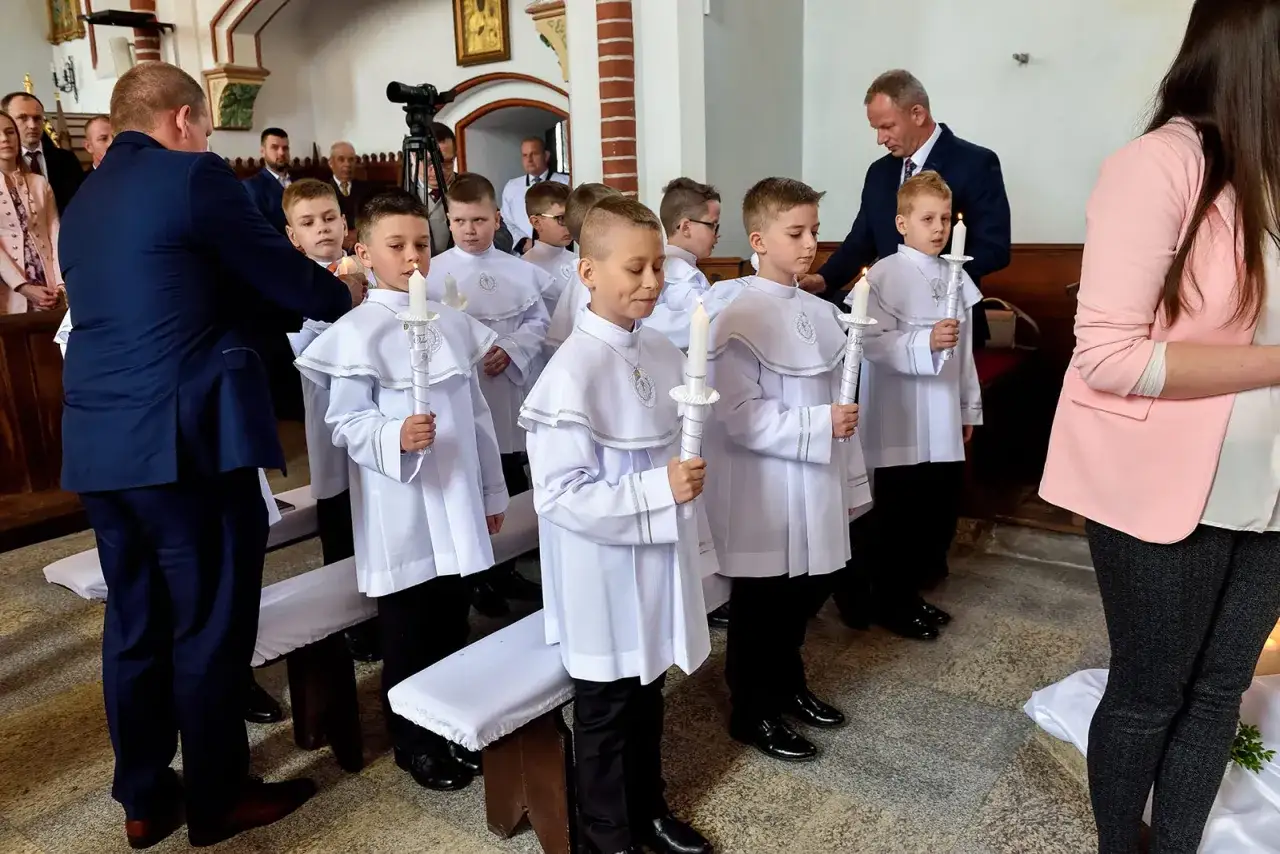 Chłopcy w białych albach z płonącymi świecami czekają na rozpoczęcie uroczystości. Zastanawiasz się, ile trwa komunia?