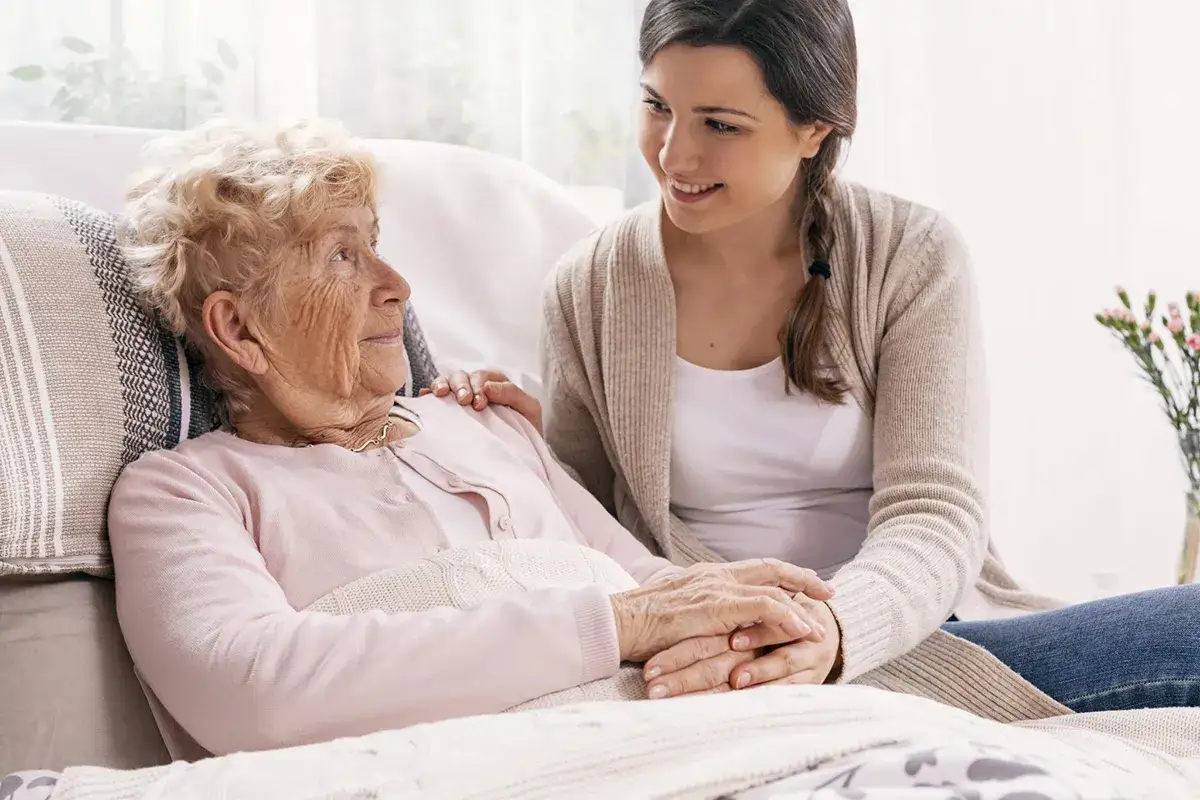 Czułe spojrzenie młodej kobiety na starszą panią. W takich chwilach bliskości można dostrzec subtelne sygnały, jak poznać że chory na alzheimera umiera.