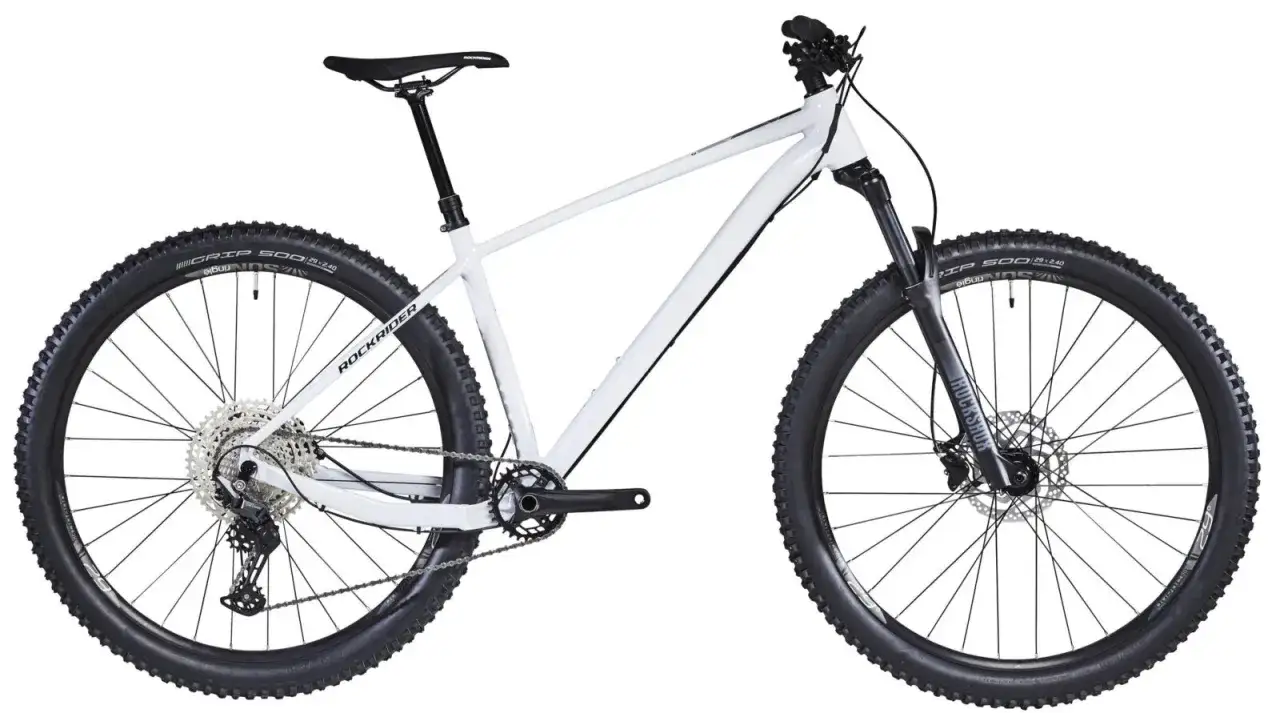 Biały rower górski Rockrider z szerokimi oponami i amortyzatorem Rockshox.
