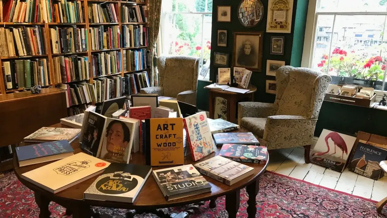Un angolo accogliente di una libreria, con scaffali pieni di libri e un tavolo centrale carico di nuove letture. Un invito al lavoro e alla scoperta.