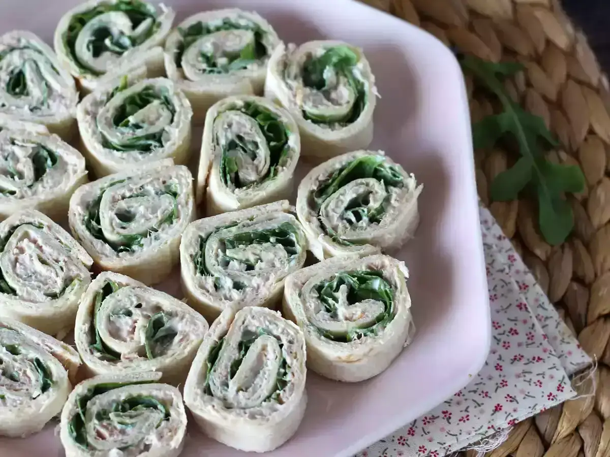 Petits rouleaux de wrap thon, cr&eacute;meux et garnis de verdure, pr&eacute;sent&eacute;s sur une assiette rose. Parfaits pour un ap&eacute;ritif l&eacute;ger.