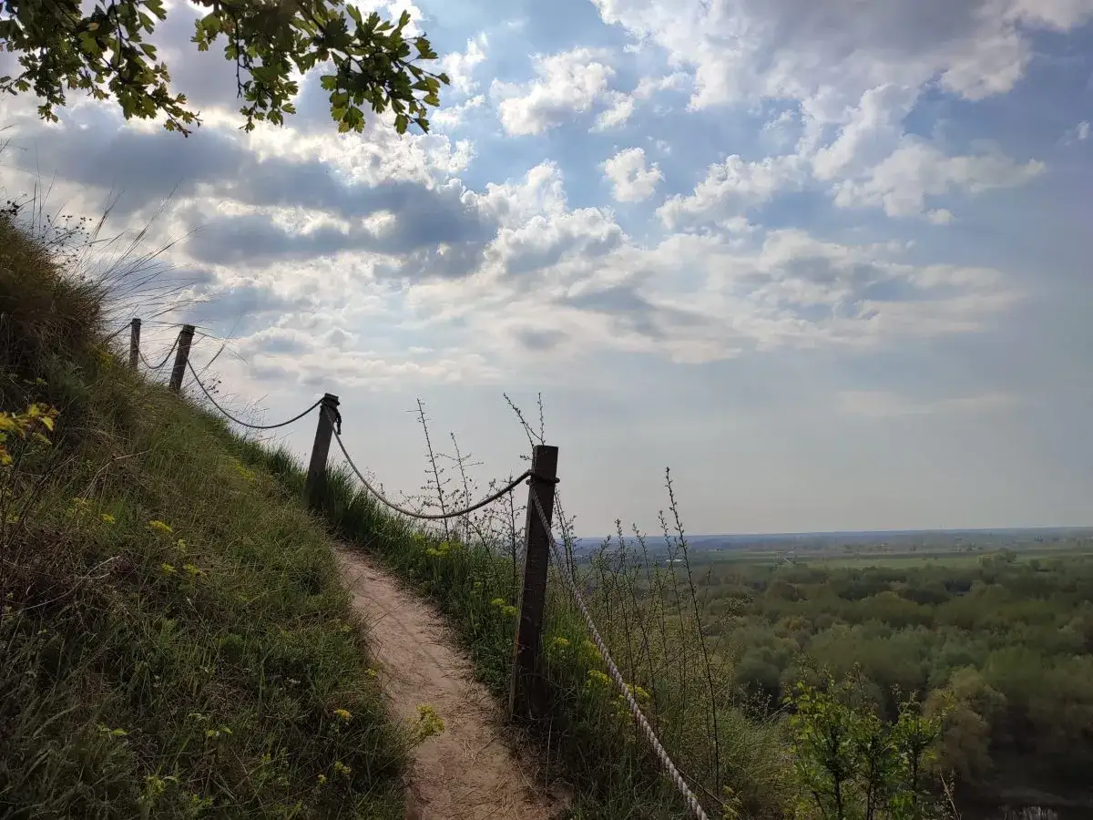 Ścieżka na zboczu Góry Pieprzowe. W oddali rozciąga się zielona dolina.