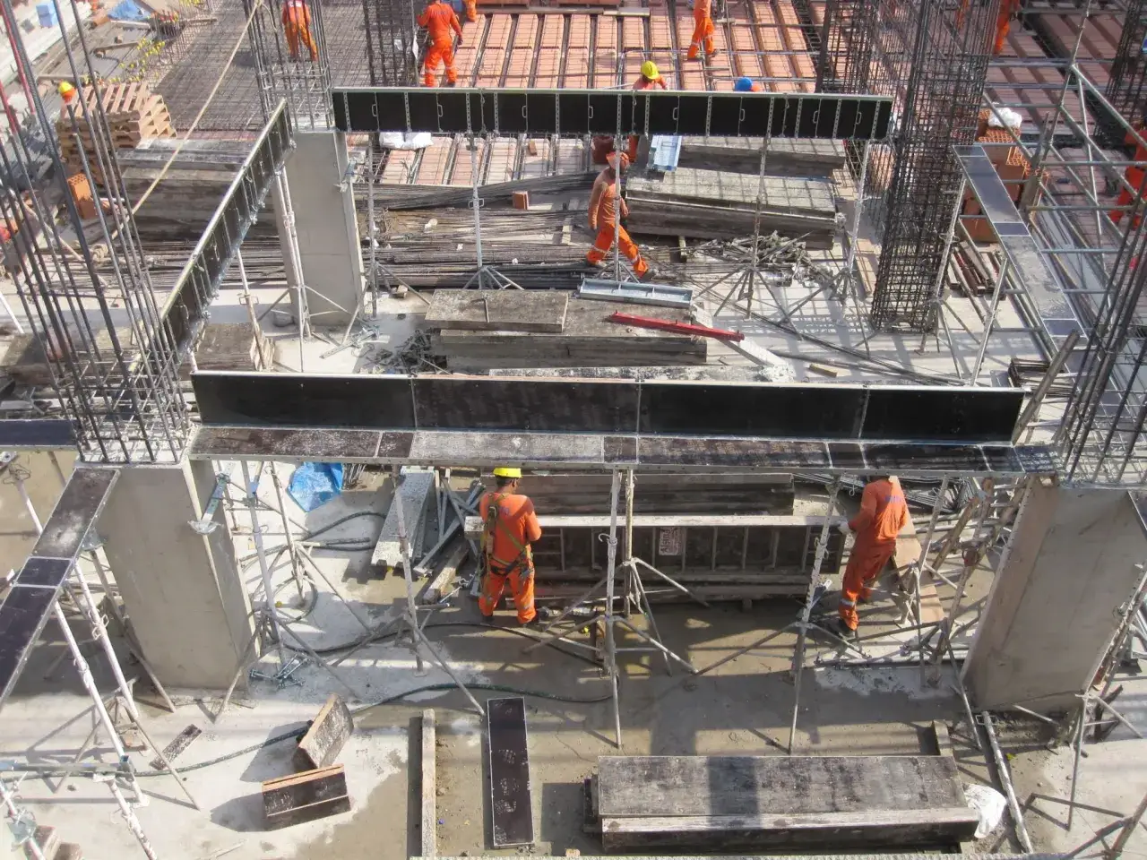 Obreros trabajan en la construcción, instalando encofrados para vigas de hormigón armado.