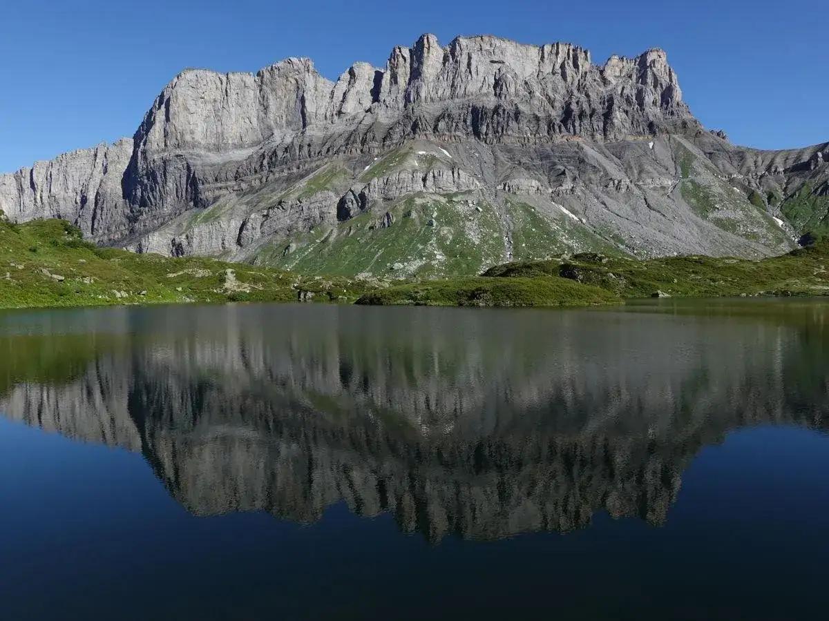 Reflet d'une montagne rocheuse dans un lac alpin paisible. Les **fîz** de la roche se dressent fièrement, reflétant leur majesté dans l'eau calme.