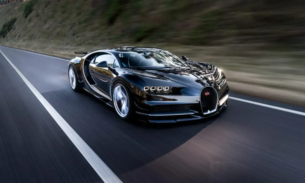 Czarny Bugatti Chiron pędzi po drodze, pokazując swoją moc w przyspieszeniu 0-100.