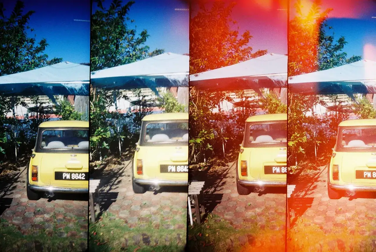 Żółty Mini Cooper pod niebieskim namiotem, uchwycony w stylu lomografii z charakterystycznymi przebarwieniami i ziarnistością.