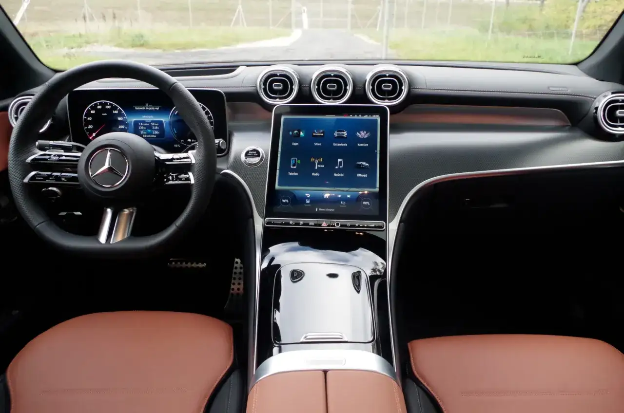 Wnętrze Mercedesa GLC 300 z brązową skórzaną tapicerką, cyfrowymi zegarami i ekranem multimedialnym.