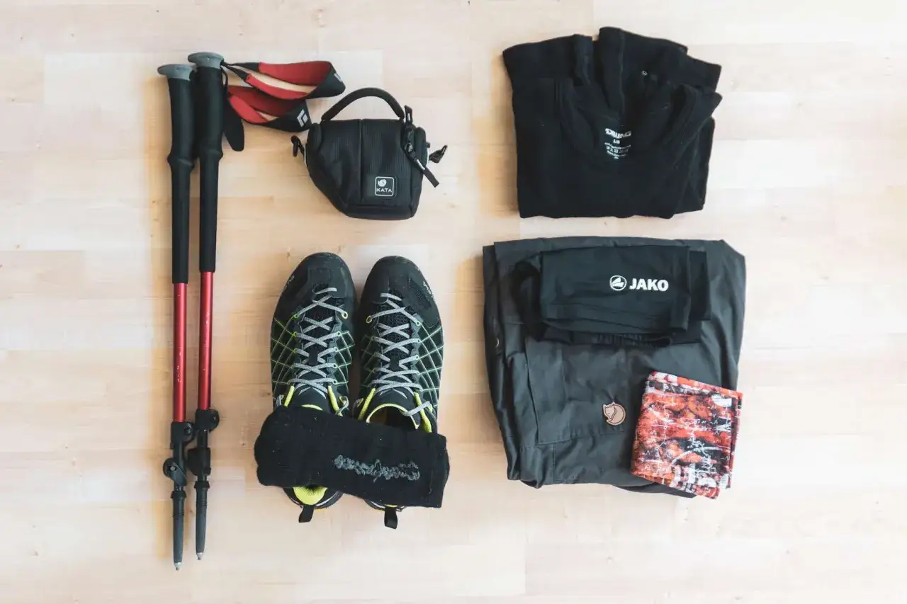 Bereit f&uuml;r das Wandern in den Alpen: Wanderschuhe, St&ouml;cke, Kleidung und eine kleine Tasche liegen bereit.