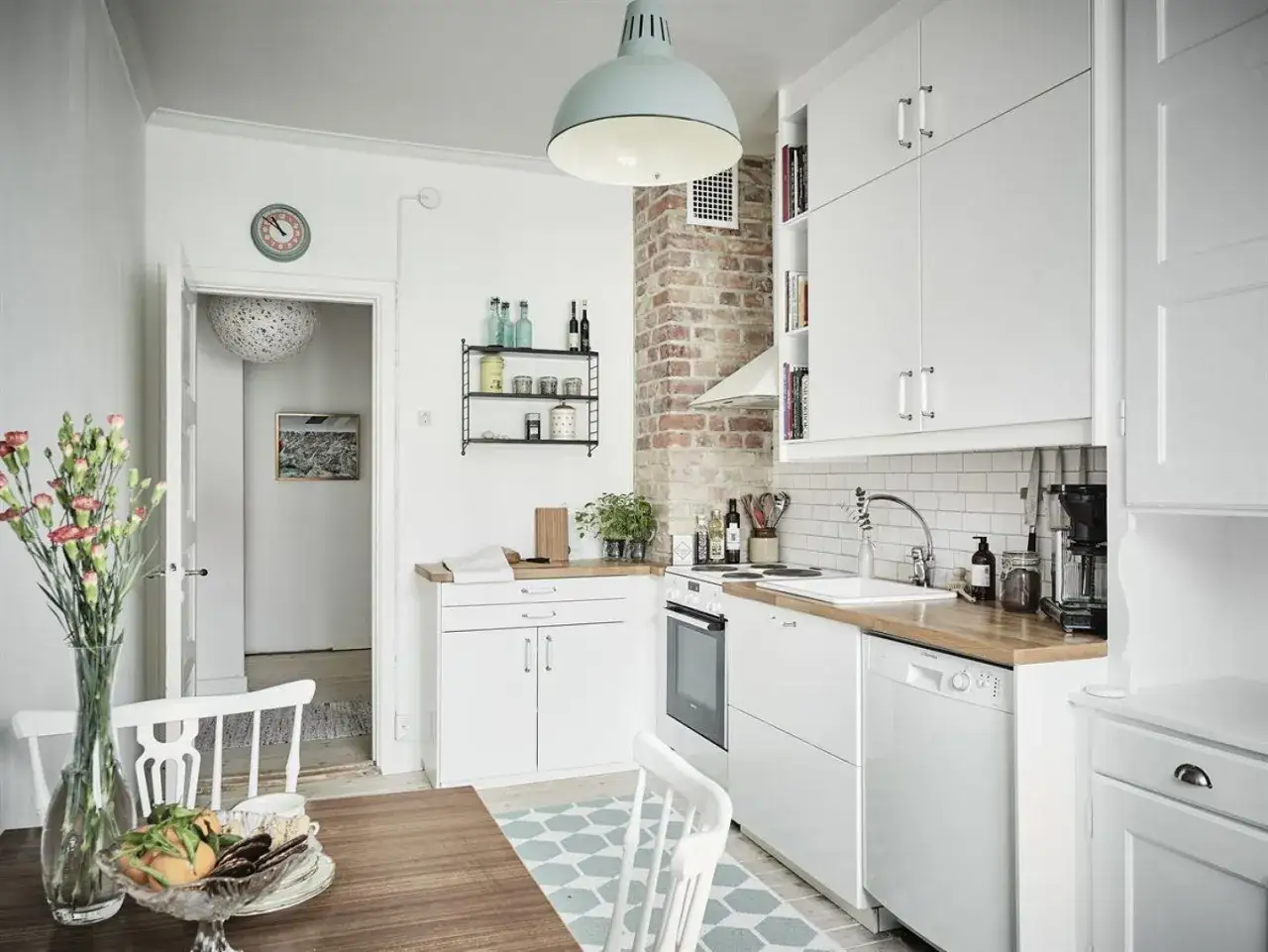 Cocina luminosa con encanto r&uacute;stico. Muebles blancos, ladrillo visto y detalles que sugieren **casas que no necesitan permiso de obra**.