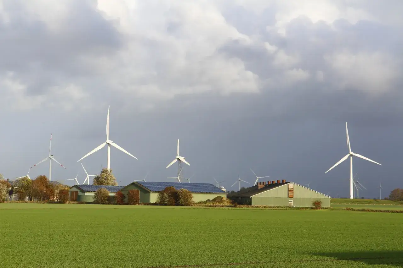 Windräder und Solarpaneele auf Gebäuden, die auf eine erfolgreiche EEG-Ausschreibung für erneuerbare Energien hindeuten.