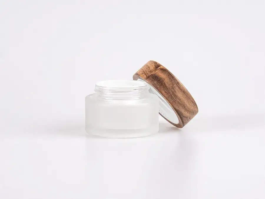 Flaschen und Tiegel mit Naturkosmetik auf Bl&auml;ttern oder Holz