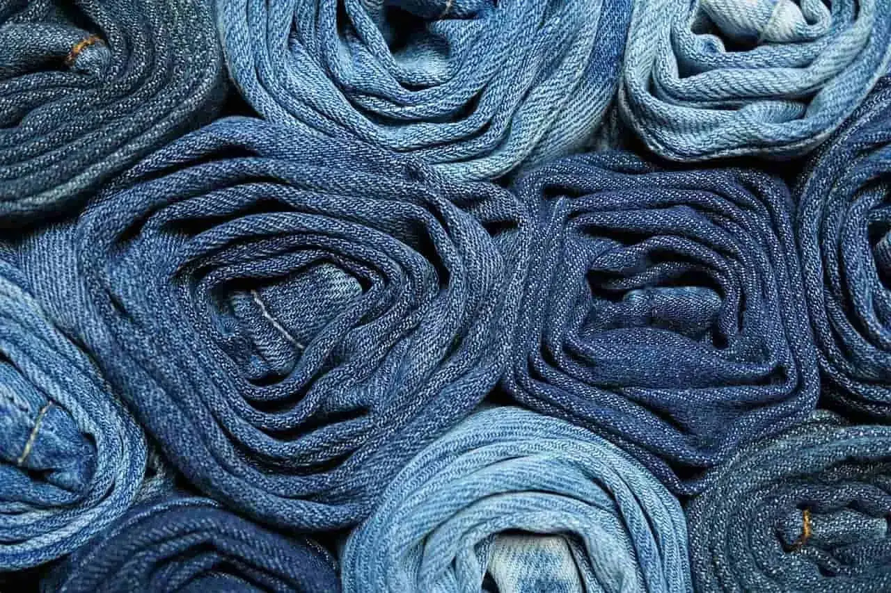 Rollos de tela vaquera en varios tonos de azul. El color denim cual es, se aprecia en esta textura de jeans enrollados.
