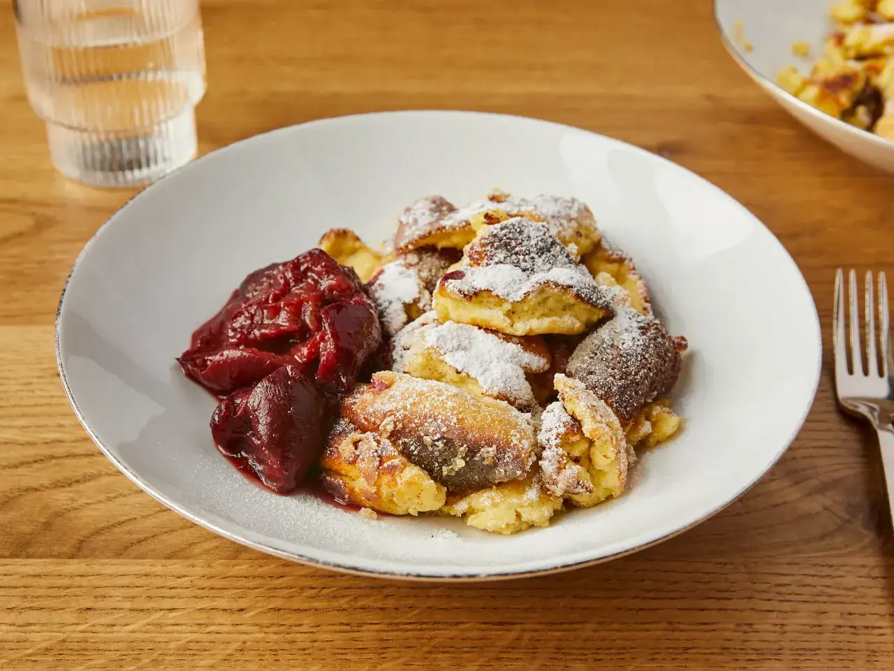Ein Teller mit Kaiserschmarrn, bestäubt mit Puderzucker, und dazu ein Klecks Zwetschgenröster.