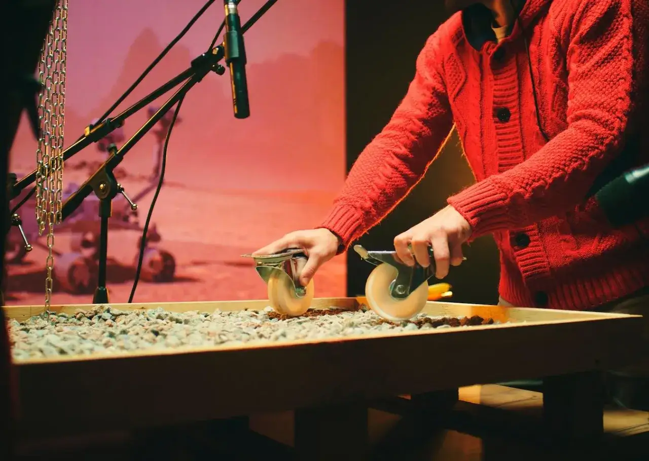 Creando sonidos para una película, este artista de foley que es, usa ruedas para simular el crujir de la grava.