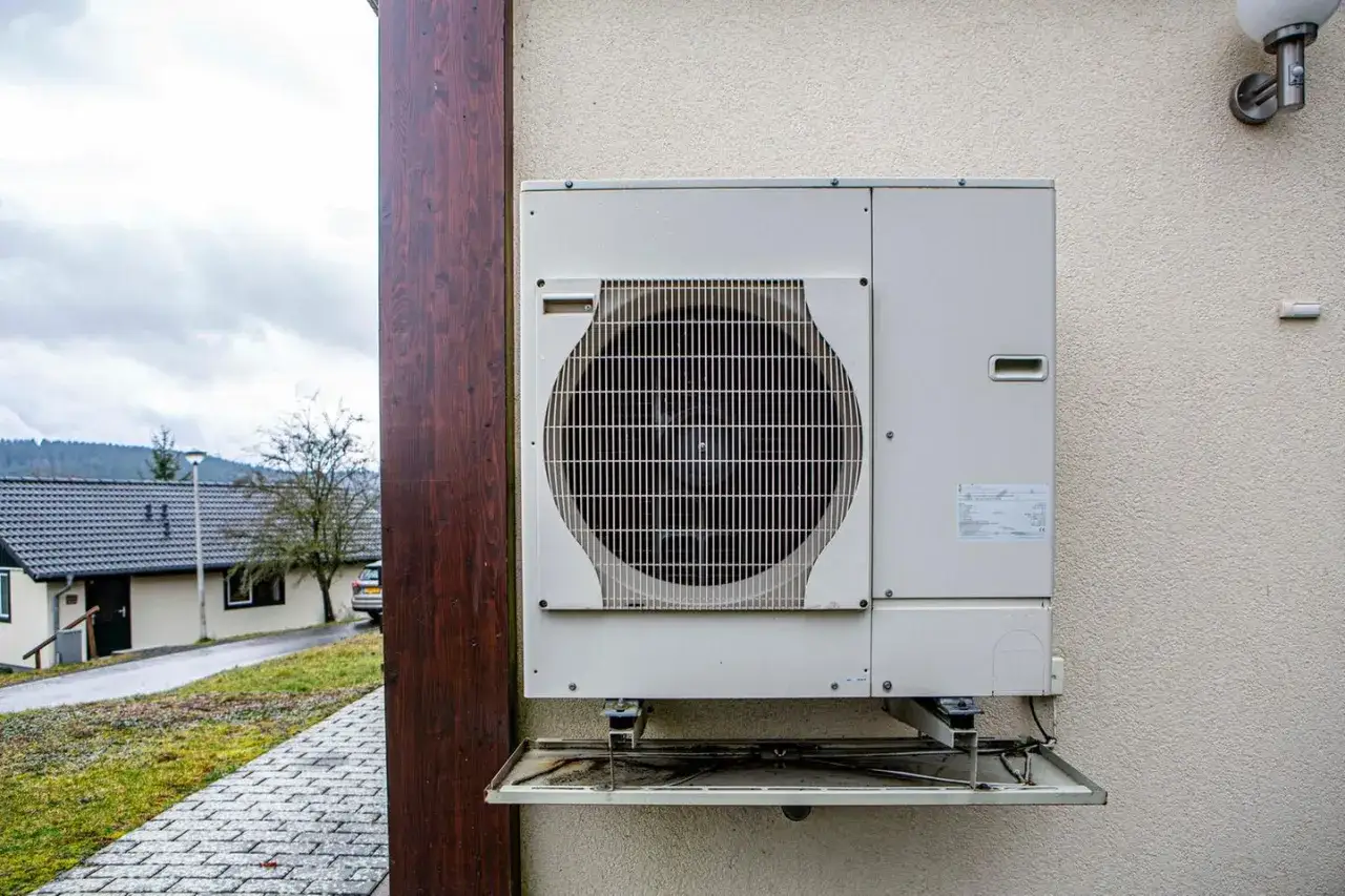 Ein Außengerät für eine Etagenheizung Gas, montiert an einer Hauswand. Im Hintergrund ein Wohnhaus und eine Straße.