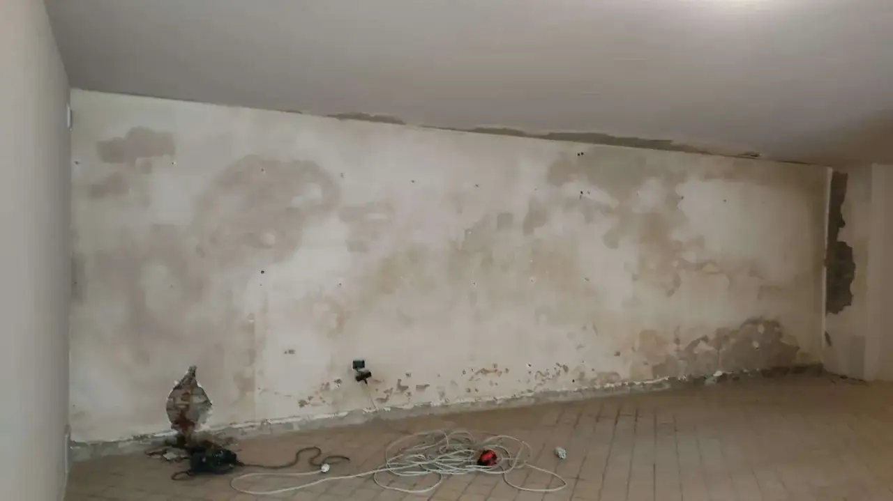 Parete con macchie di umidità, un buco nel muro e cavi a terra. Ideale per chi cerca come rivestire una parete umida.