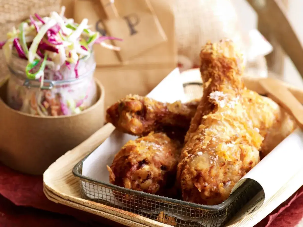 Krispig friterad kyckling med en fräsch coleslaw i bakgrunden. Perfekt för en avslappnad måltid.