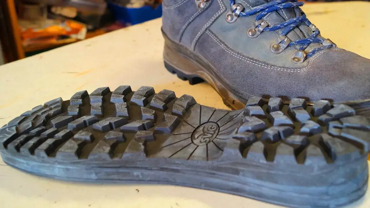 Ein grauer Wanderschuh liegt neben seiner abgenommenen, profilierten Sohle. Bereit, die Wanderschuhe neu besohlen zu lassen f&uuml;r neue Abenteuer.