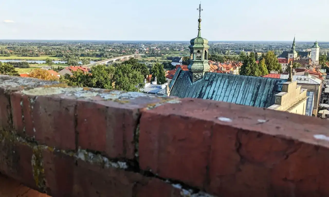 Widok na Sandomierz z murów obronnych. Widać dachy kamienic, wieże kościołów i Wisłę. To piękne sandomierskie atrakcje.