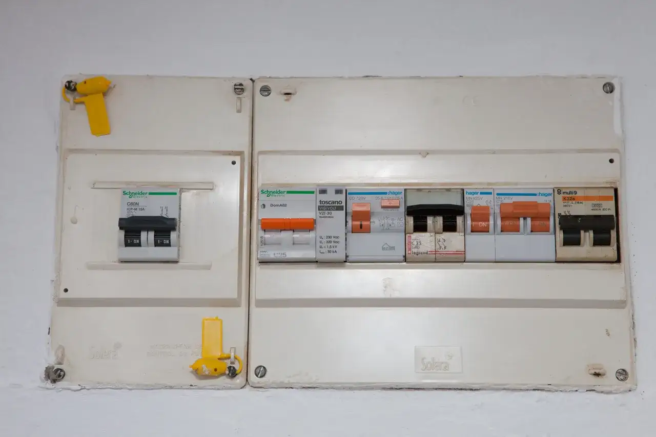 Cuadro eléctrico de vivienda con varios interruptores automáticos y un precinto de seguridad amarillo.