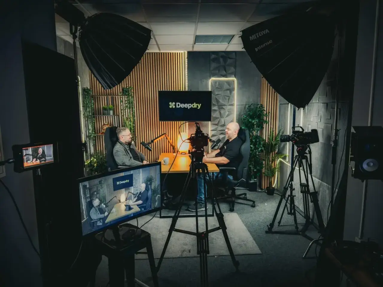 Dwóch mężczyzn nagrywa marketing podcast w studiu. Widać kamery, mikrofony i oświetlenie.
