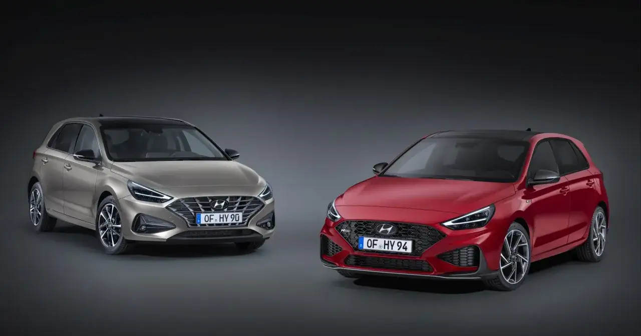 Dwa modele Hyundai i30 2024: jeden w kolorze złotym, drugi czerwony, prezentują swoje sportowe linie i nowoczesny design.