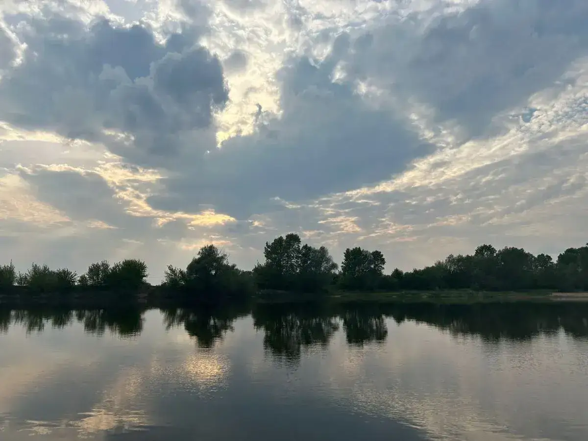 Spokojna rzeka odbija chmury i drzewa. Taka piękna pogoda we wrześniu, idealna na spacer.
