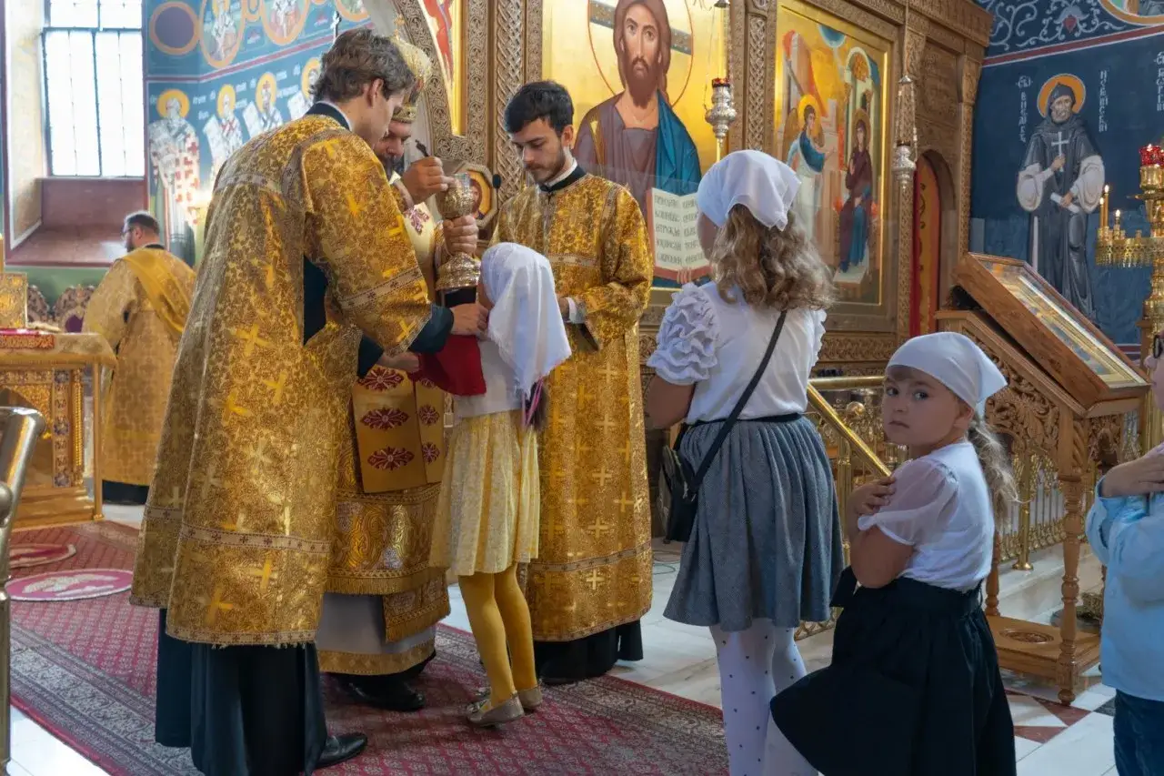 Dzieci w cerkwi podczas spowiedzi świętej. Duchowni w złotych szatach udzielają błogosławieństwa.