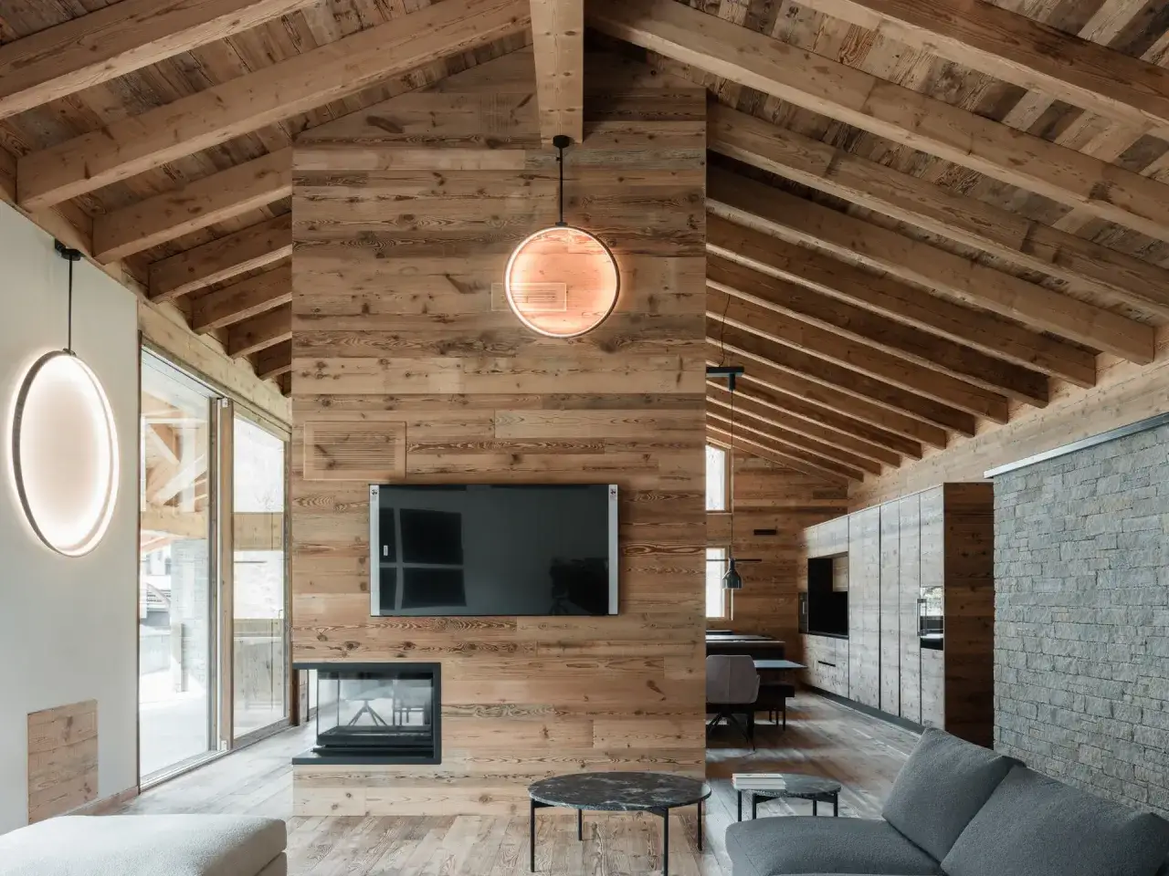 Gem&uuml;tliche luxus chalet inneneinrichtung mit Holzw&auml;nden, Kamin, moderner Beleuchtung und Blick auf die Berge.