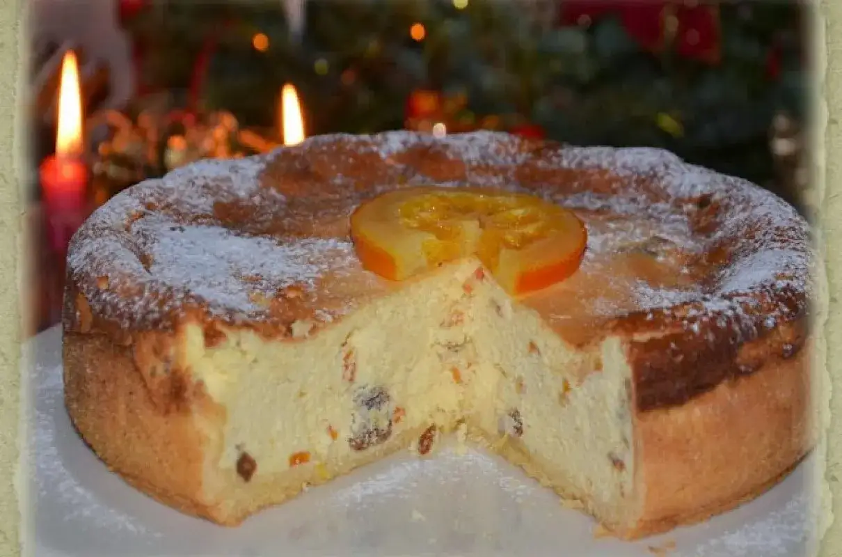Pyszny sernik tradycyjny, idealny na święta. Prosty przepis, puszyste ciasto z bakaliami, ozdobione pomarańczą i cukrem pudrem.